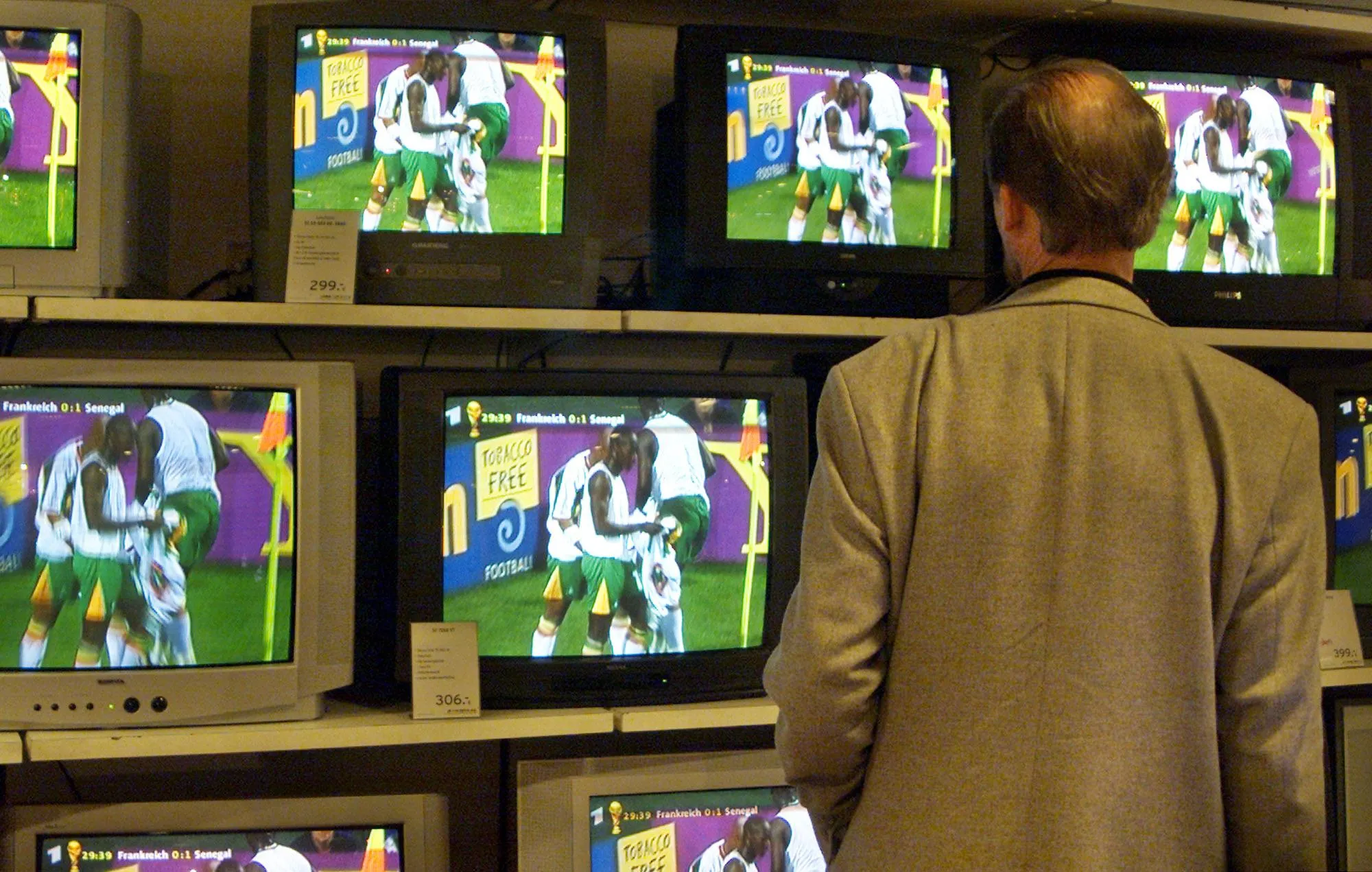 A man watches Senegal's celebrations against France on a wall of TV screens in a department store in downtown Hamburg