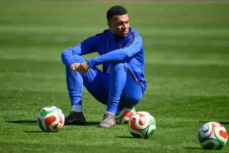 Kylian Mbappé sitting on a football