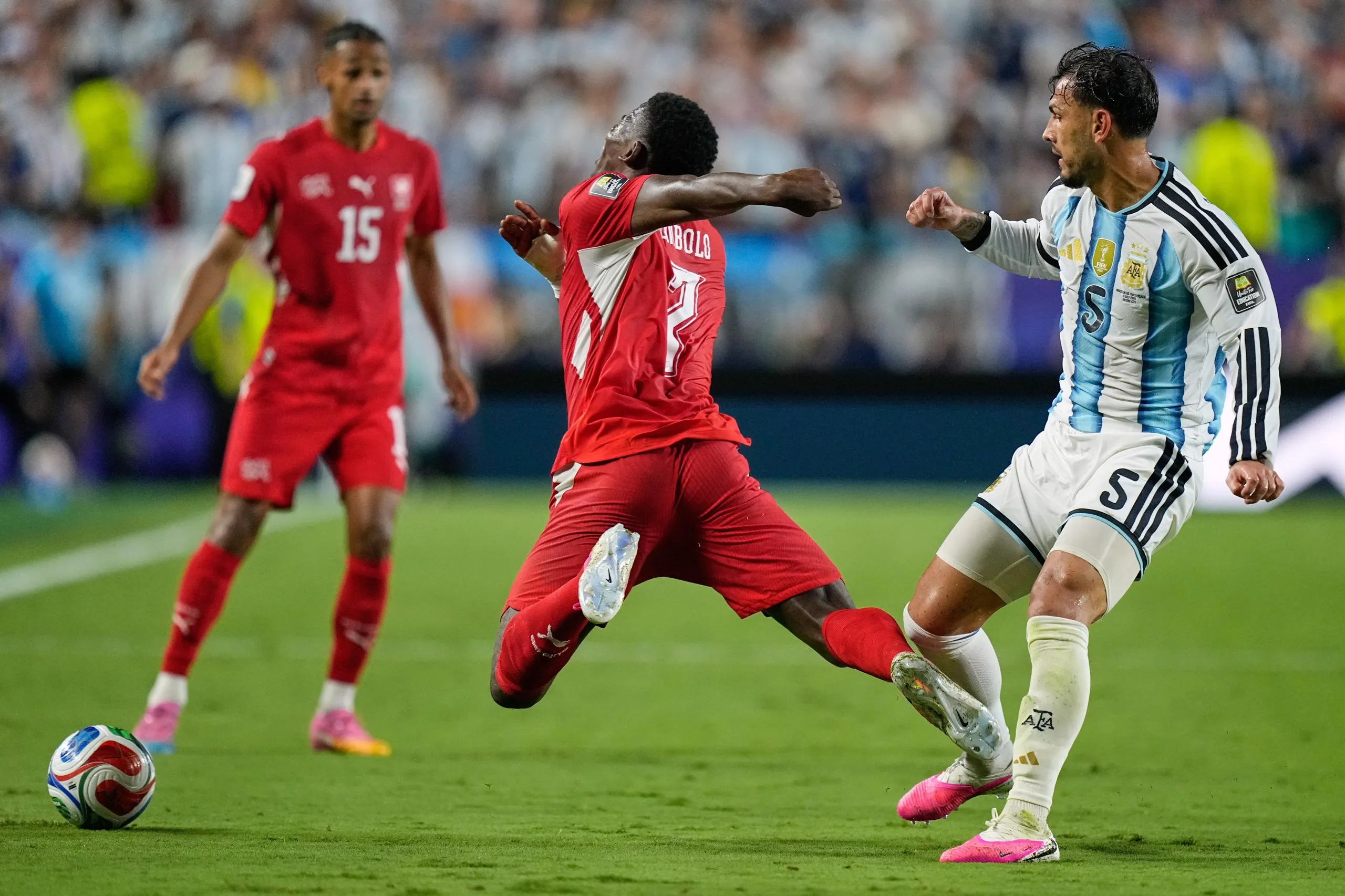 Switzerland’s Breel Embolo falls to ground under pressure from Argentina’s Leandro Paredes in a 2026 World Cup quarter-final